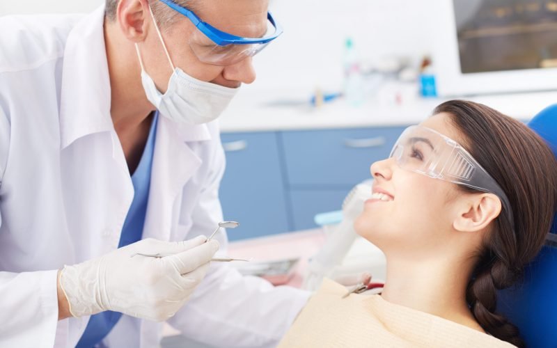 Young happy girl looking at the dentist during oral checkup